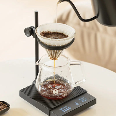 Coffee brewing process using a pour-over setup with a digital scale on a light surface.