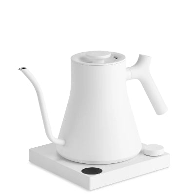 A white electric gokuroh kettle with a long spout and handle, resting on a matching white charging dock with a small black indicator light, set against a solid white background.
