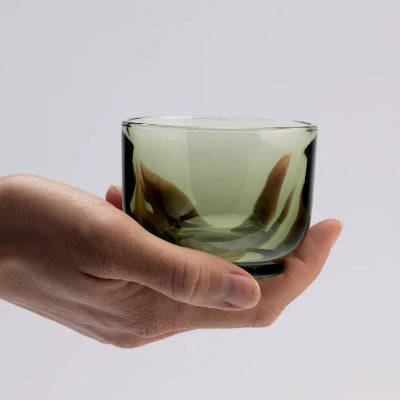 Hand holding a green glass against a white background