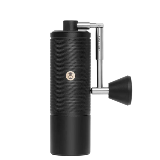 Black manual coffee grinder with a silver handle on a white background