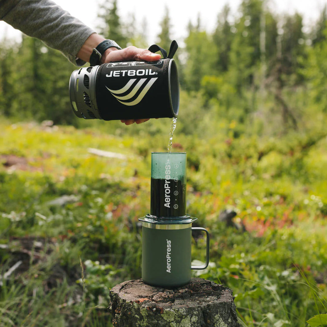 Person using a Jetboil stove in a forest setting