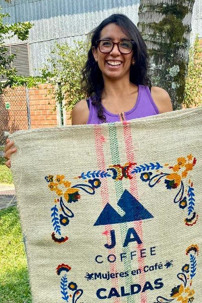 Woman holding a JA Coffee Caldas coffee bag outdoors