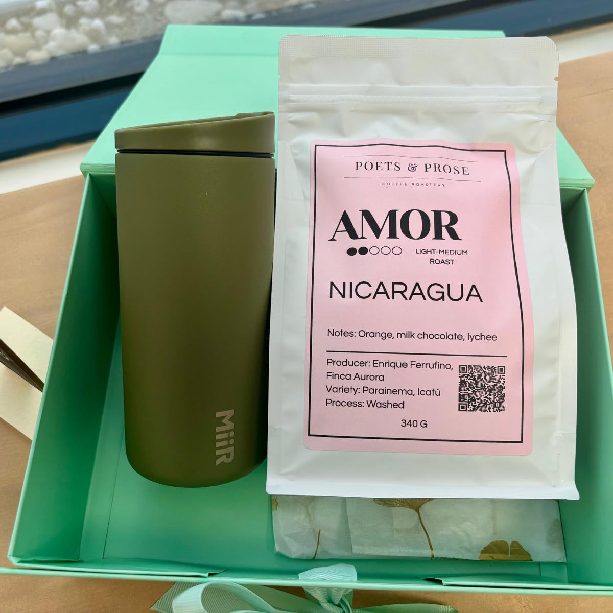 Green coffee container with a pink label on a wooden surface