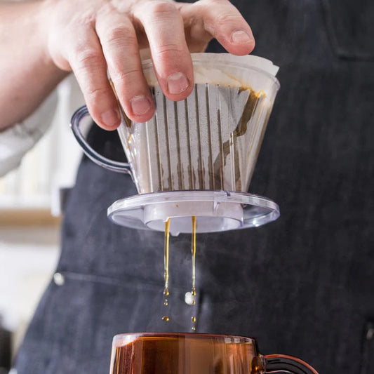 Person pouring coffee from a filter into a mug