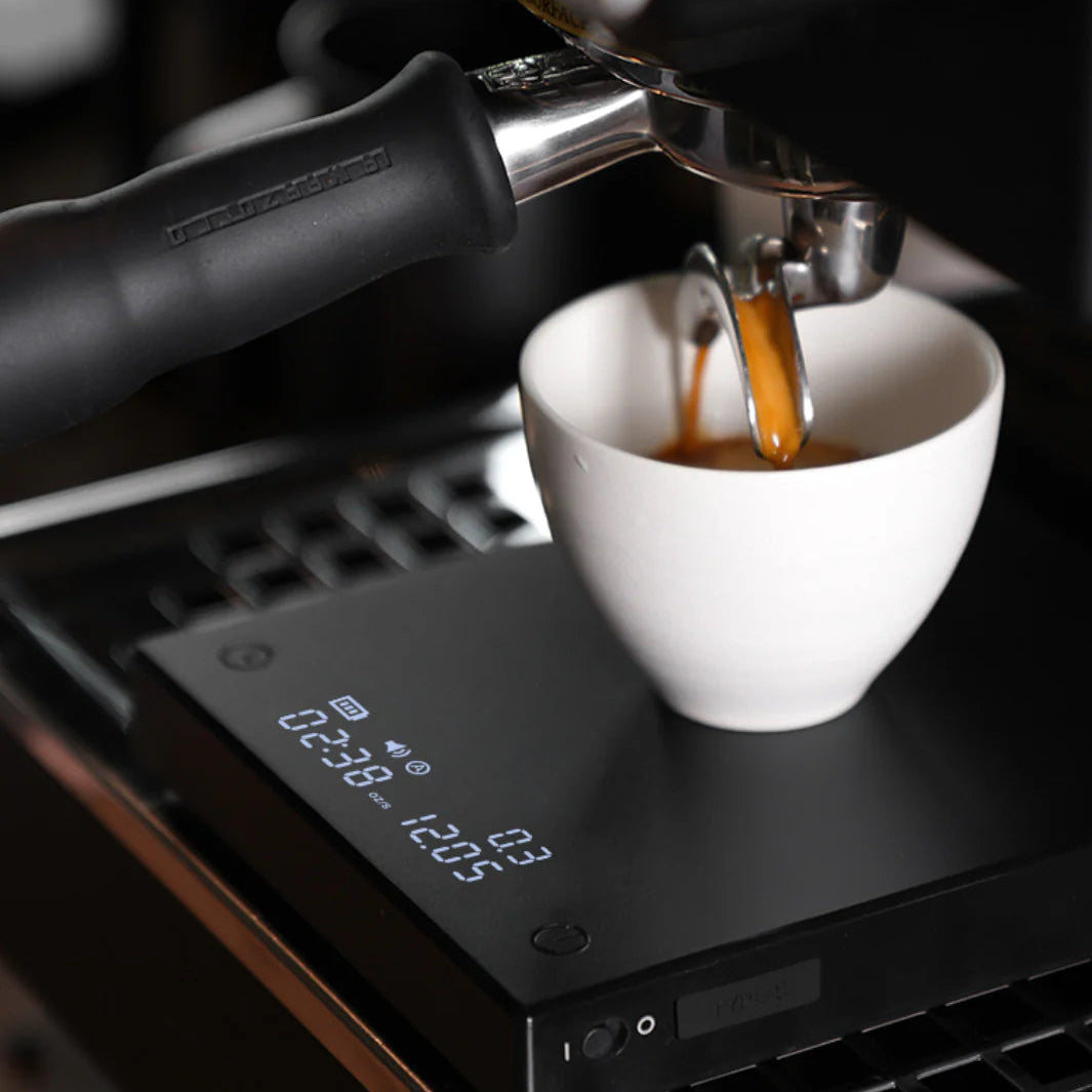 Espresso being poured from a machine into a white cup.